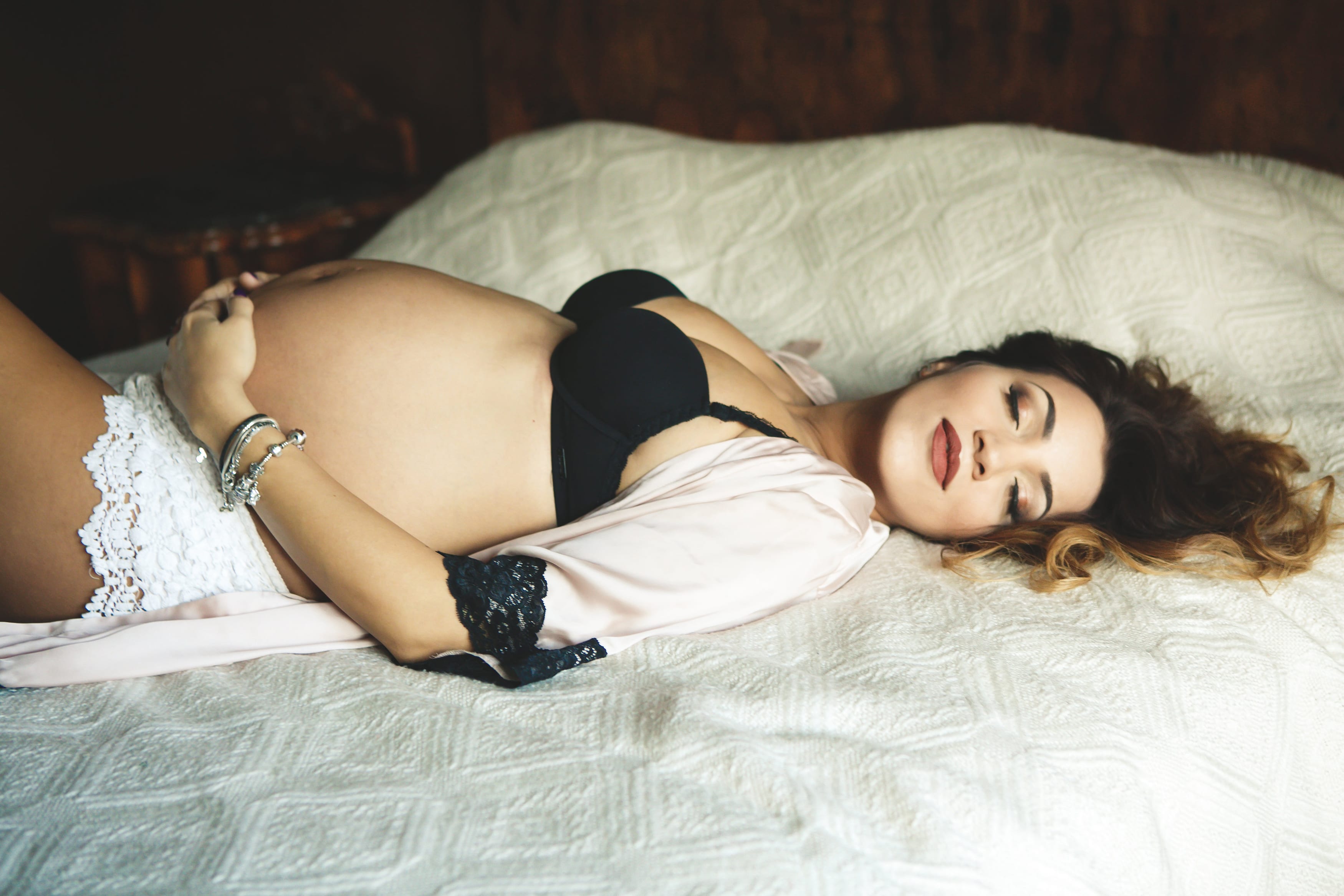 Schwangere Frau auf Bett in Dessous bei einem Babybauch Shooting