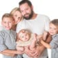 Familie mit Mutter Vater und zwei Kindern und einem kleinen Baby posiert waehrend eines Familienfotos von Donna Bellini Photo Studio Berlin