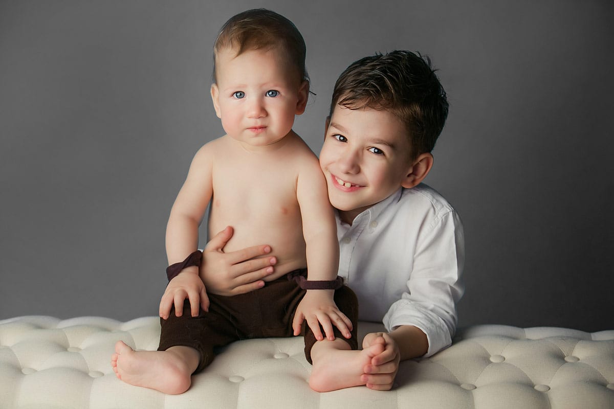 Junge mit kleinem Babybruder posiren waehrend eines Familienfotoshooting in Donna Bellini Photo Studio Berlin